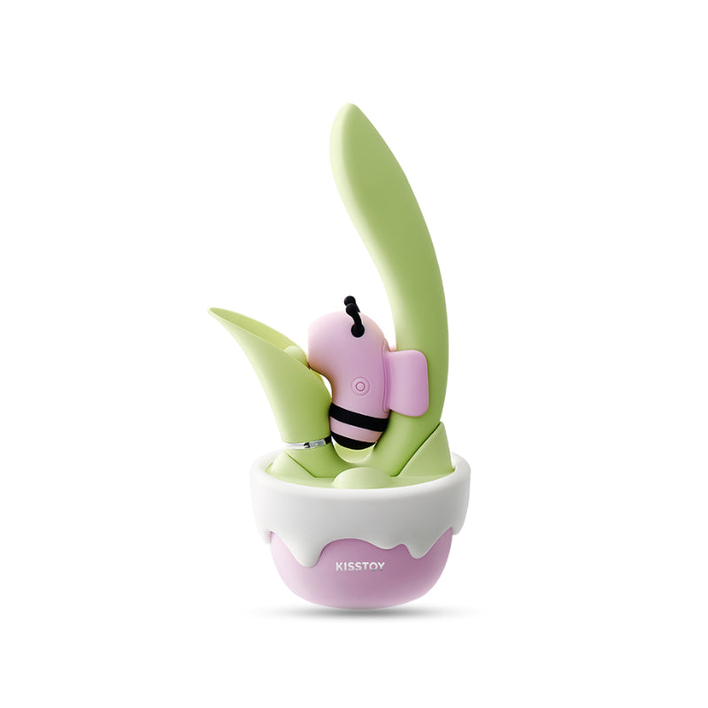 Pink bee-shaped suction stimulator with striped body resting in a green leaf wand and pink flower-pot base