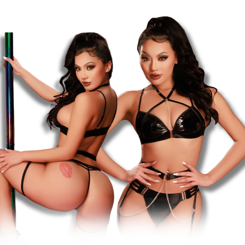 Two women wearing black faux-leather strappy lingerie set with bra, garter belt, and shorts.